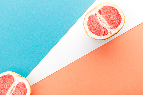 Top view of grapefruit halves on blue, orange and white background