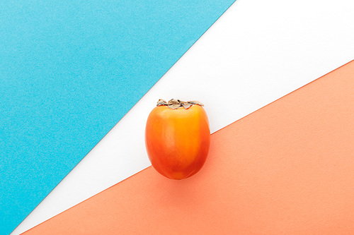 Top view of persimmon on white, orange and blue background
