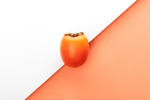 Top view of persimmon on white and orange background