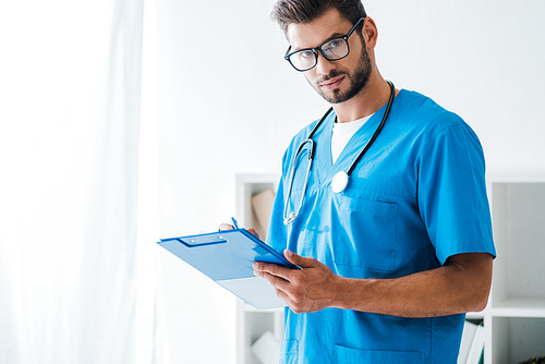 handsome, confident veterinarian writing on clipboard while 