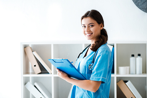 beautiful veterinarian smiling at camera while writing prescription on clipboard