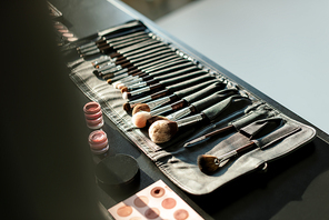 selective focus of makeup brush set near lip balms and eye shadows