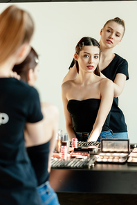 selective focus of make up artist near model and decorative cosmetics