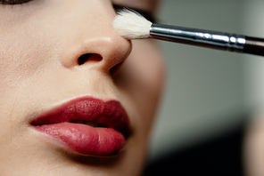 selective focus of cosmetic brush near woman with red lips