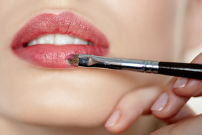 cropped view of makeup artist applying lipstick on girl