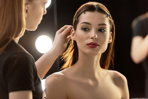 selective focus of makeup artist touching hair of young model