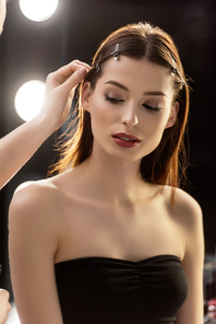 makeup artist touching hair of beautiful model