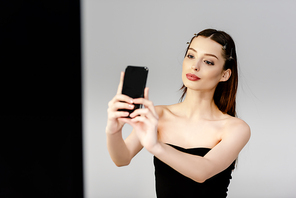 beautiful woman taking selfie on grey and black