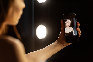 selective focus of woman taking selfie in photo studio