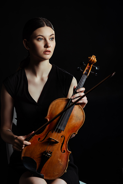 beautiful professional musician holding violin isolated on black