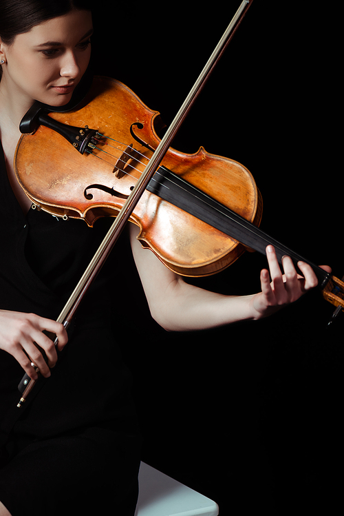 attractive female musician playing on violin on dark stage