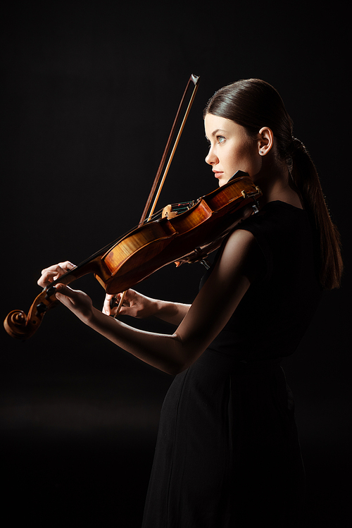 attractive female musician playing on violin isolated on black