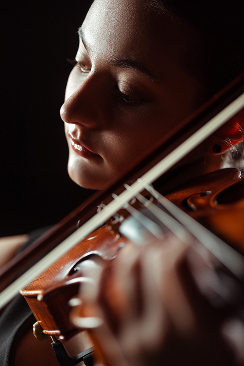 beautiful professional musician playing symphony on violin isolated on black, selective focus