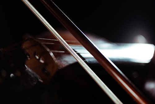 close up of violin and bow in dark, selective focus