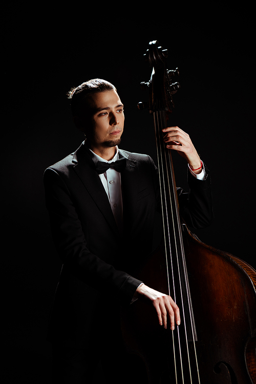 male professional musician playing on contrabass isolated on black