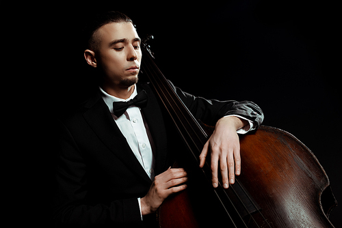 young musician playing on double bass isolated on black