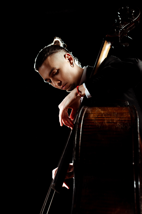 male professional musician playing on double bass isolated on black