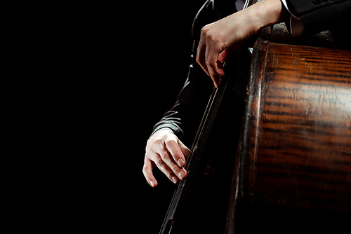 partial view of male professional musician playing on contrabass isolated on black