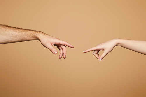 cropped view of man and woman reaching each other with fingers isolated on beige