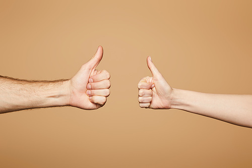 cropped view of man and woman showing thumbs up isolated on beige