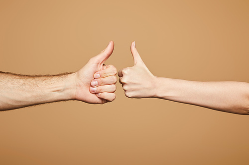 cropped view of man and woman showing thumbs up isolated on beige