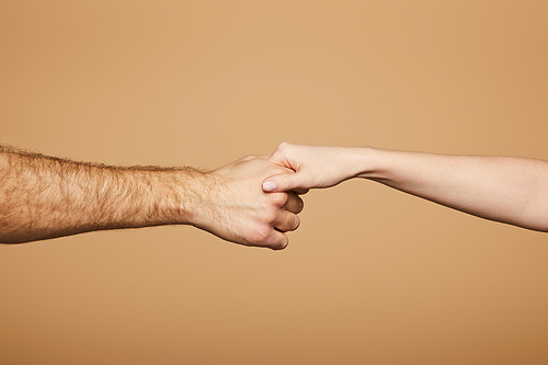 cropped view of man holding hand of woman isolated on beige