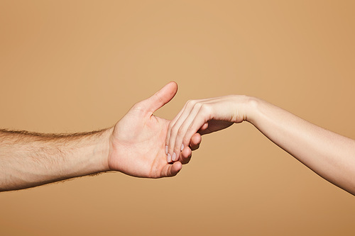 cropped view of man holding hand of woman isolated on beige