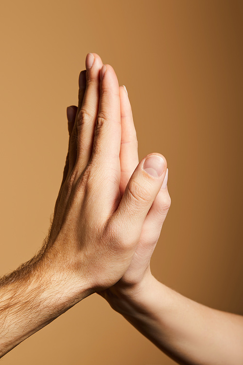 cropped view of man and woman giving high five on beige