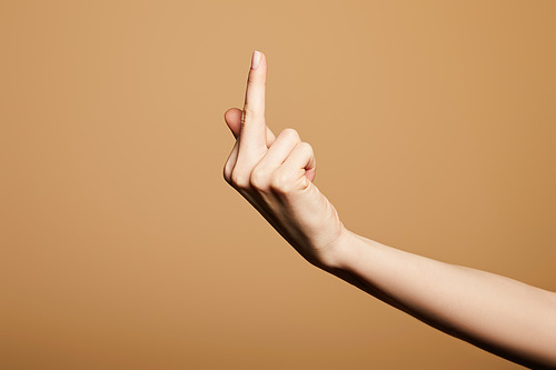 cropped view of woman showing middle finger isolated on beige