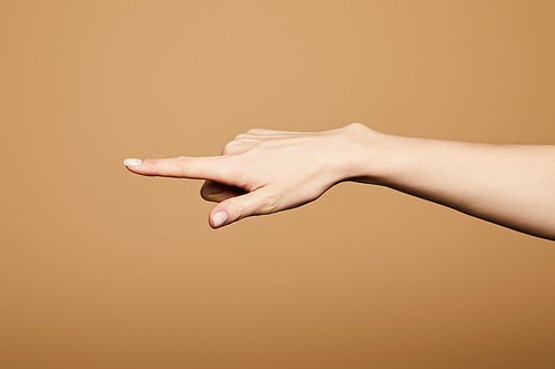 cropped view of woman pointing with finger isolated on beige