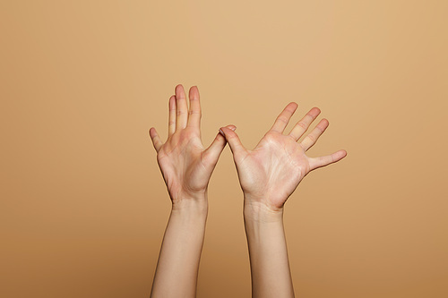 cropped view of woman showing palms isolated on beige