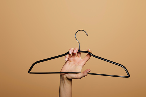 cropped view of woman holding empty hanger isolated on beige