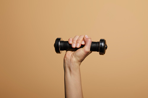 cropped view of woman holding dumbbell isolated on beige