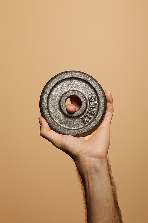 cropped view of man holding weight isolated on beige