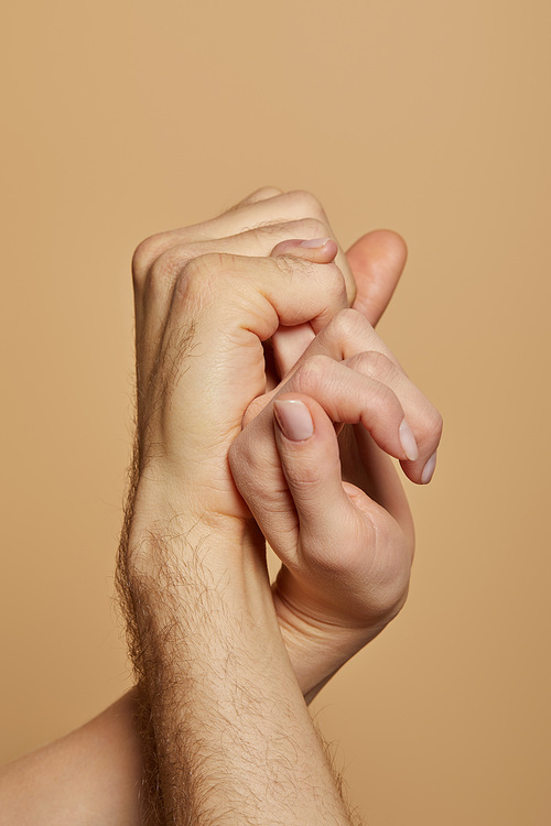 cropped view of man and woman holding little fingers isolated on beige