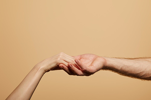 cropped view of man holding woman hand isolated on beige