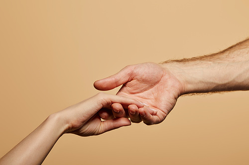 cropped view of man holding woman hand isolated on beige