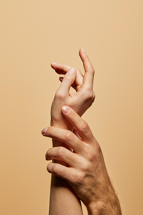 cropped view of man touching woman hand isolated on beige