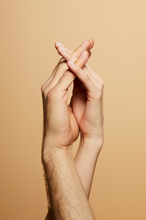 cropped view of man and woman holding hands isolated on beige