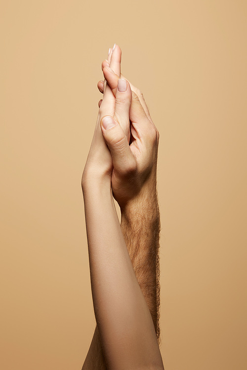 partial view of man and woman holding hands isolated on beige