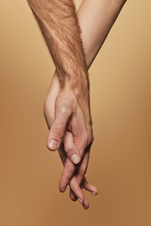 partial view of man and woman holding hands isolated on beige