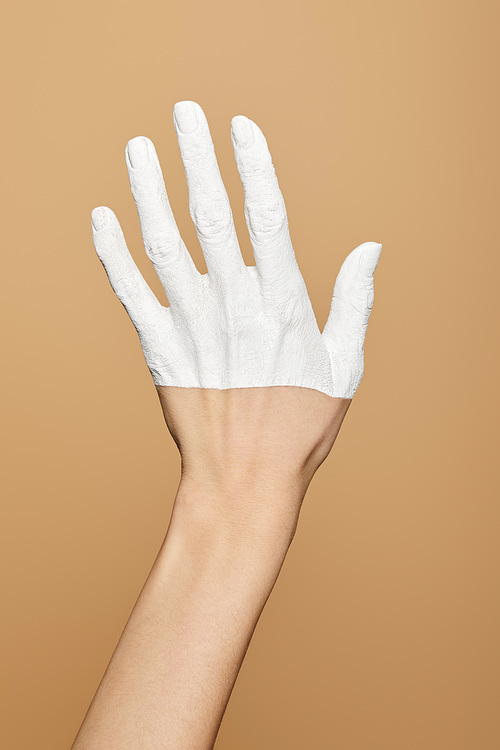 cropped view of woman with white painted hand isolated on beige