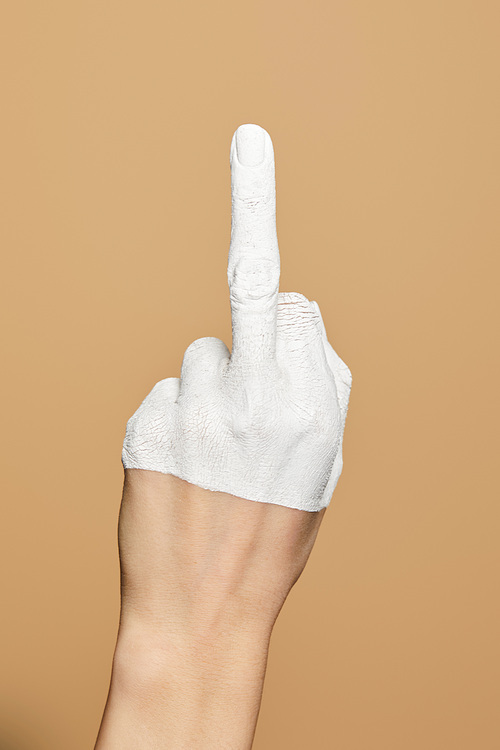 cropped view of woman with white painted hand showing middle finger isolated on beige