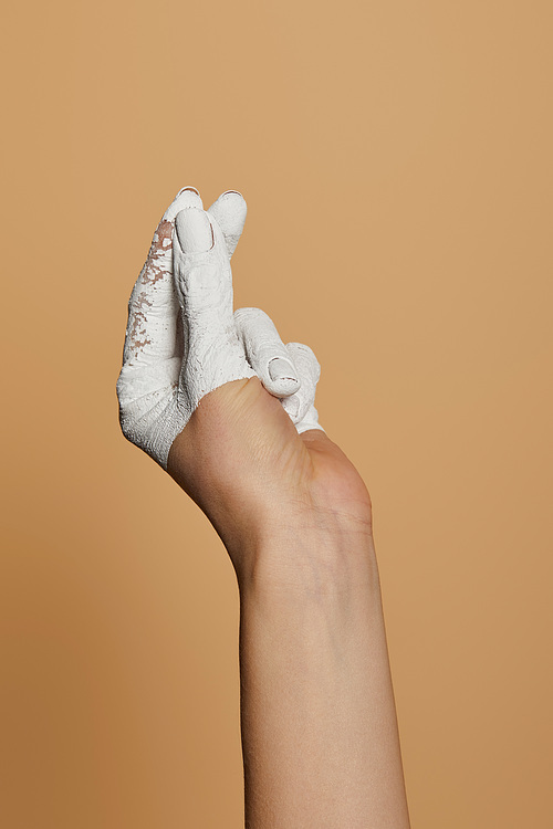 cropped view of woman with white painted hand sowing money gesture isolated on beige