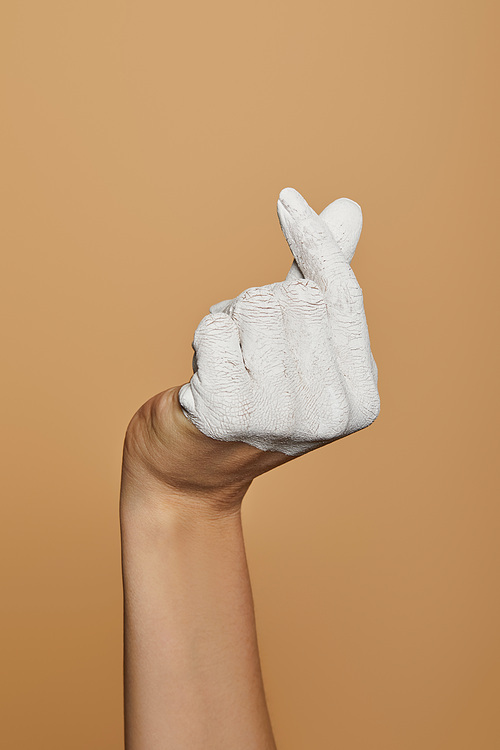 cropped view of woman with white painted hand isolated on beige