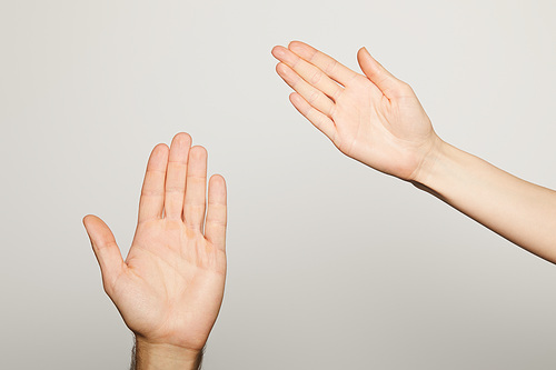 cropped view of man and woman showing palms isolated on grey