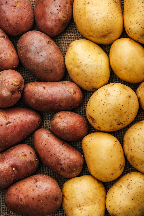 top view of organic raw potatoes on brown rustic sackcloth