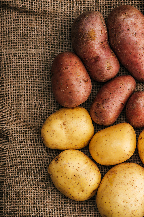 top view of organic raw potatoes on brown rustic sackcloth