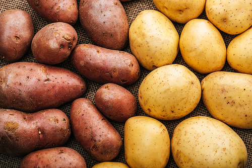 top view of organic raw potatoes on brown rustic sackcloth