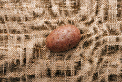 top view of organic raw potato on brown rustic sackcloth